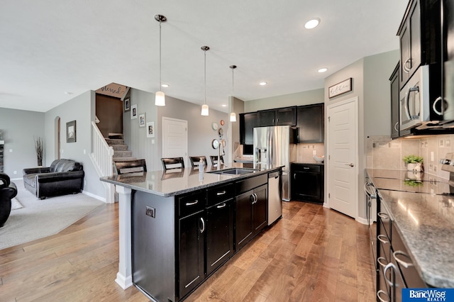 7308 Andy Dr, Lincoln, NE 68516 - kitchen with appliances with stainless steel finishes, a sink, light wood finished floors, open floor plan, and pendant lighting