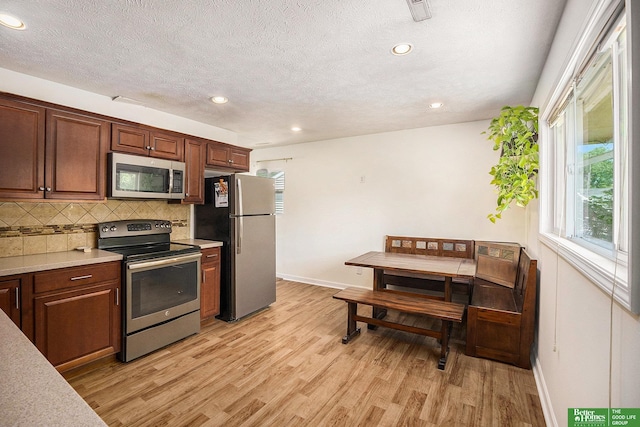 kitchen featuring appliances with stainless steel finishes, light wood-type flooring, backsplash, baseboards, and recessed lighting