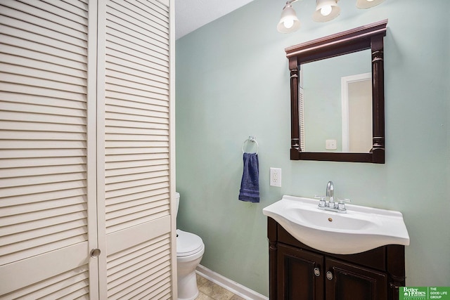 bathroom featuring toilet, vanity, and baseboards