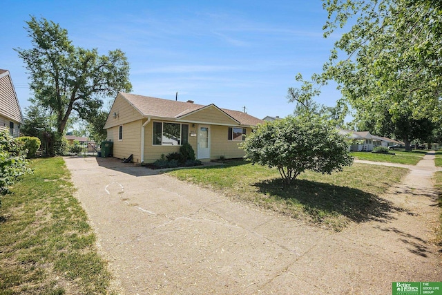 view of front of home with asphalt driveway, roof with shingles, and a front lawn