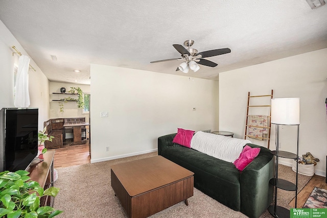 living area with a ceiling fan, baseboards, and wood finished floors
