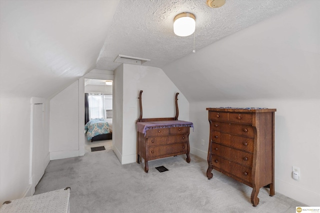 bedroom featuring lofted ceiling, carpet floors, and a textured ceiling