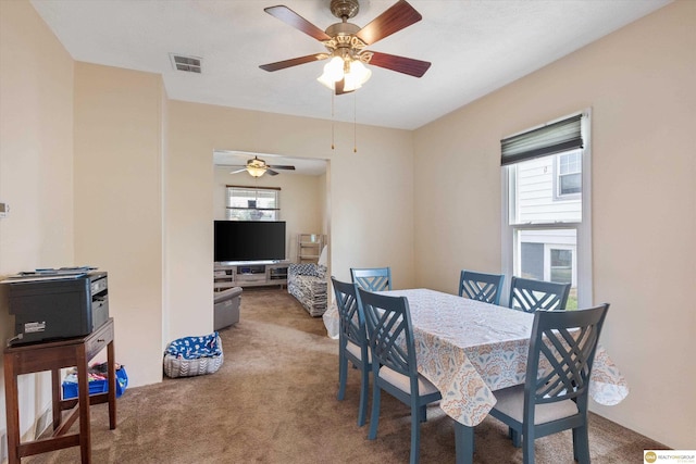 carpeted dining space with plenty of natural light and a ceiling fan