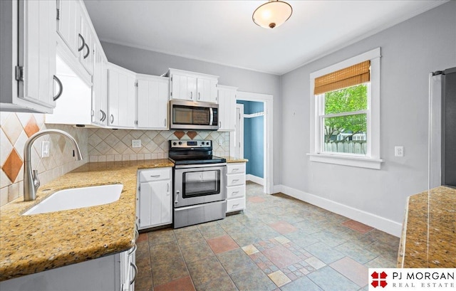5107 Cuming St, Omaha, NE 68132 - kitchen with appliances with stainless steel finishes, a sink, baseboards, backsplash, and white cabinetry