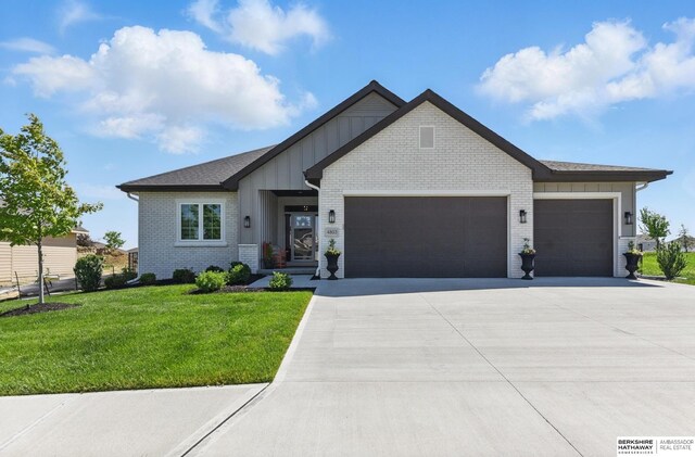 4803 N 192nd Ave, Elkhorn, NE 68022 - view of front of home featuring an attached garage, board and batten siding, concrete driveway, a front yard, and brick siding