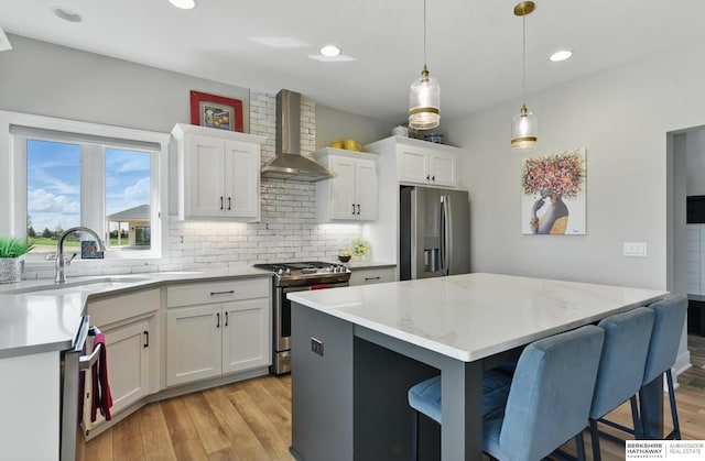 4803 N 192nd Ave, Elkhorn, NE 68022 - kitchen featuring stainless steel appliances, wall chimney range hood, a sink, light wood-style flooring, and tasteful backsplash