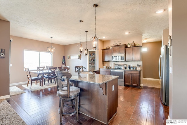 8902 N 161st Ave, Bennington, NE 68007 - kitchen with stainless steel appliances, a sink, a textured ceiling, baseboards, and dark wood finished floors