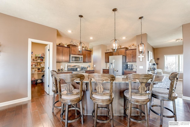8902 N 161st Ave, Bennington, NE 68007 - kitchen with stainless steel appliances, brown cabinets, dark wood-style floors, and a spacious island