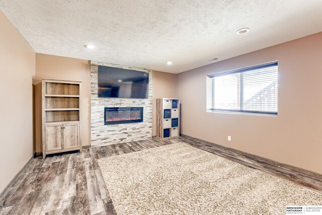 8902 N 161st Ave, Bennington, NE 68007 - unfurnished living room featuring wood finished floors, a textured ceiling, a large fireplace, baseboards, and recessed lighting