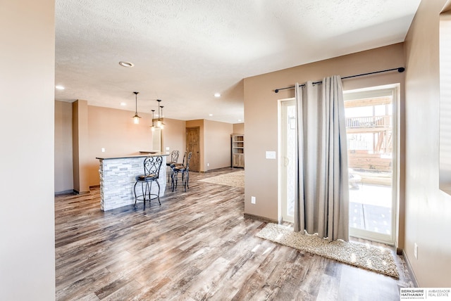 8902 N 161st Ave, Bennington, NE 68007 - kitchen with light wood-type flooring, a kitchen island with sink, pendant lighting, a textured ceiling, and baseboards