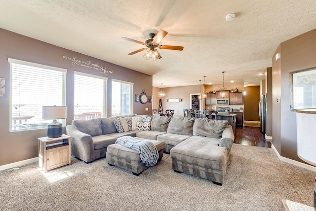 8902 N 161st Ave, Bennington, NE 68007 - living room featuring a ceiling fan, dark colored carpet, a textured ceiling, baseboards, and a chandelier