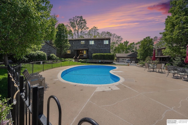 pool at dusk featuring fence and a patio