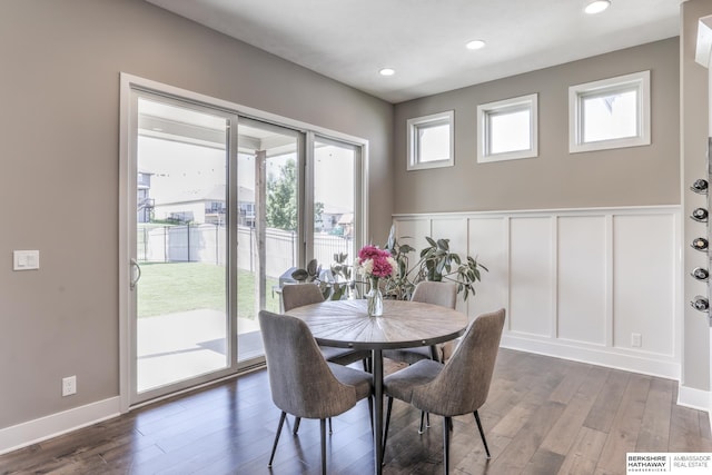 dining room with a decorative wall, wood finished floors, wainscoting, and recessed lighting