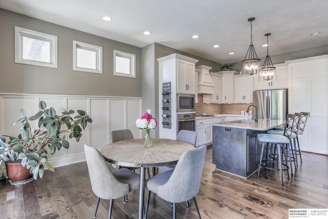 dining room featuring dark wood-style floors, a decorative wall, wainscoting, and recessed lighting
