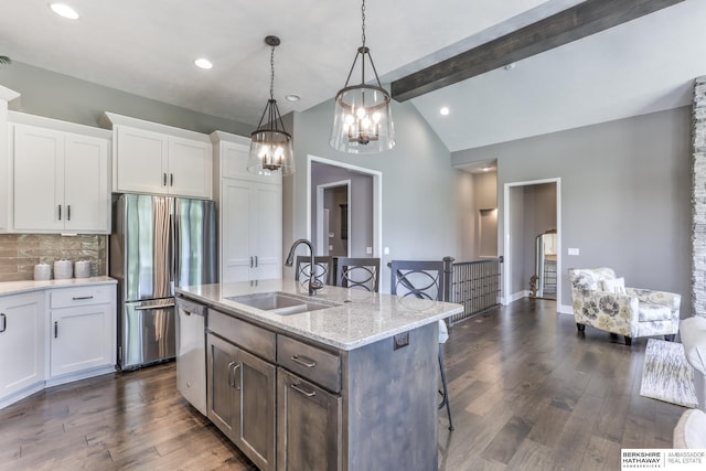kitchen with a sink, appliances with stainless steel finishes, a breakfast bar, decorative backsplash, and white cabinets