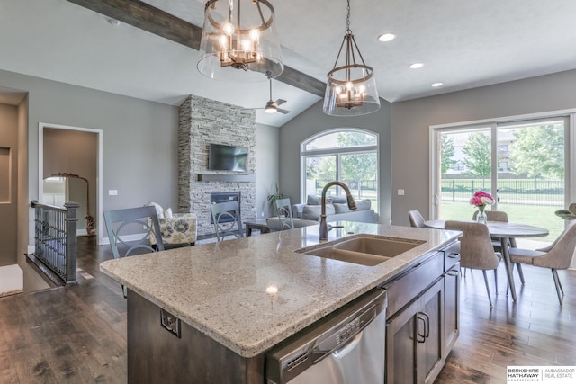 kitchen with dishwasher, a sink, a chandelier, dark wood-style flooring, and a fireplace