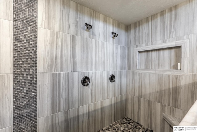 bathroom featuring a tile shower and a textured ceiling