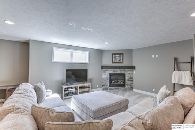 living room featuring recessed lighting, a textured ceiling, a stone fireplace, baseboards, and carpet
