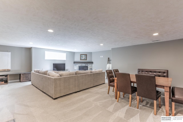 living area with light colored carpet, a fireplace, recessed lighting, and a textured ceiling