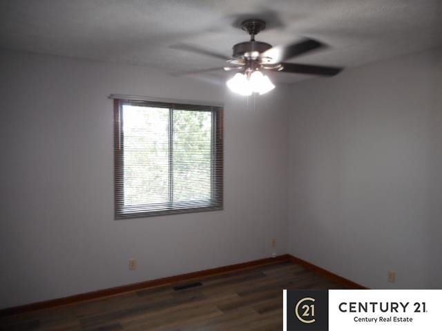 unfurnished room featuring a ceiling fan, dark wood finished floors, and baseboards