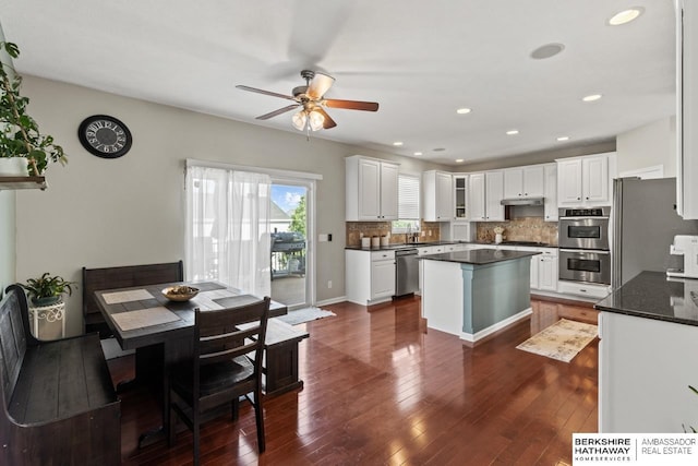 8917 N 157th St, Bennington, NE 68007 - kitchen featuring appliances with stainless steel finishes, a ceiling fan, a center island, tasteful backsplash, and dark wood-type flooring