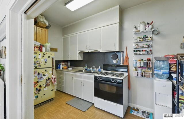 401 S 38th Ave, Omaha, NE 68131 - kitchen with freestanding refrigerator, gas range oven, white cabinetry, light countertops, and a sink