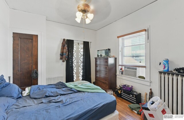 401 S 38th Ave, Omaha, NE 68131 - bedroom featuring radiator heating unit, wood finished floors, cooling unit, and a ceiling fan