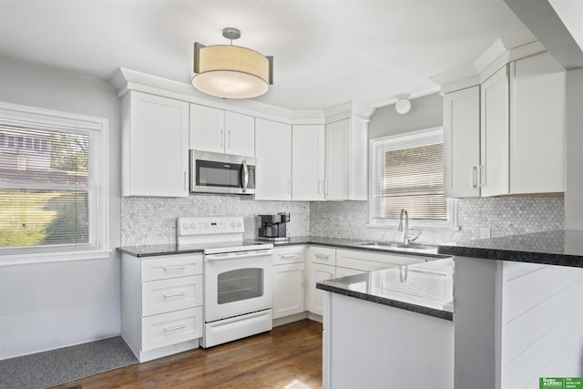 4921 Charles St, Omaha, NE 68132 - kitchen with stainless steel microwave, white electric stove, a sink, white cabinetry, and a peninsula