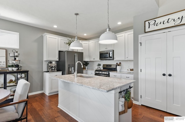 kitchen with appliances with stainless steel finishes, a sink, dark wood-type flooring, recessed lighting, and an island with sink