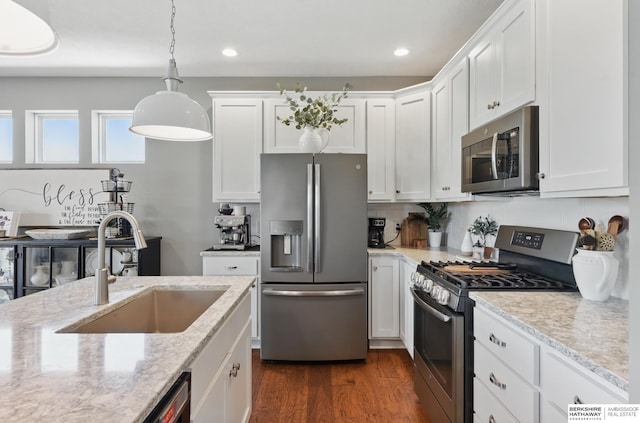 kitchen with stainless steel appliances, a sink, white cabinets, dark wood-style floors, and backsplash