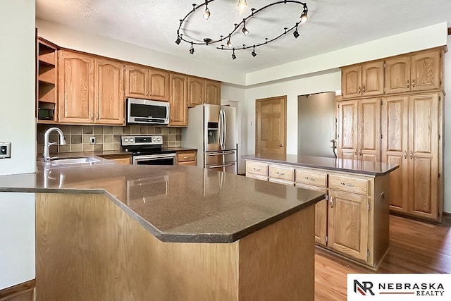 kitchen with stainless steel appliances, a sink, a peninsula, and dark countertops