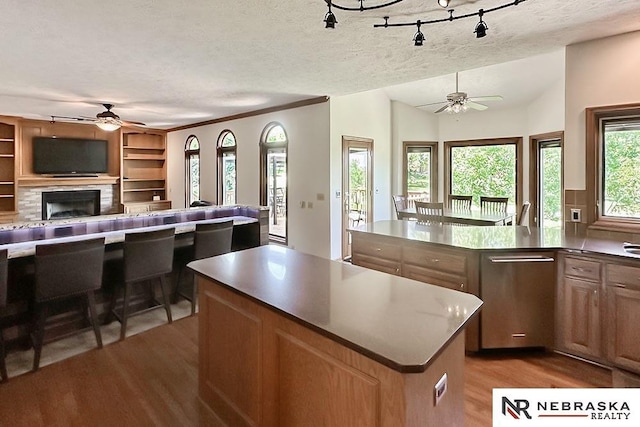 kitchen featuring ceiling fan, open floor plan, wood finished floors, a textured ceiling, and a kitchen island