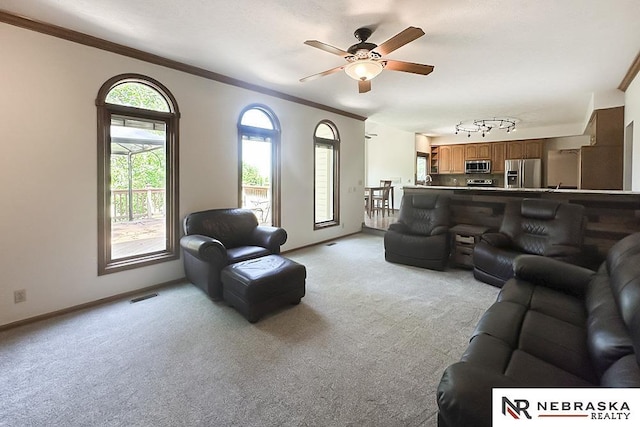 living area featuring light colored carpet, a ceiling fan, crown molding, and baseboards
