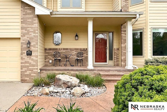 view of exterior entry featuring a porch and brick siding