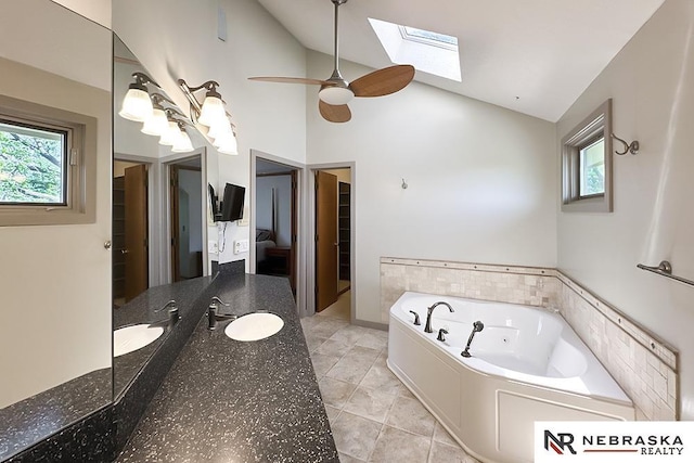 bathroom with a whirlpool tub, a skylight, a ceiling fan, tile patterned flooring, and vanity