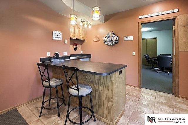 bar area featuring light tile patterned floors, decorative light fixtures, light carpet, and baseboards