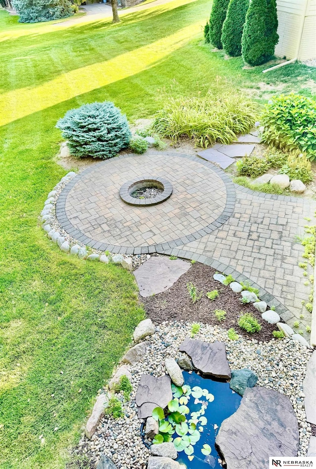 view of grassy yard featuring an outdoor fire pit, a patio area, and golf course view
