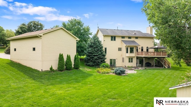 rear view of house with a wooden deck, stairway, a lawn, and a chimney
