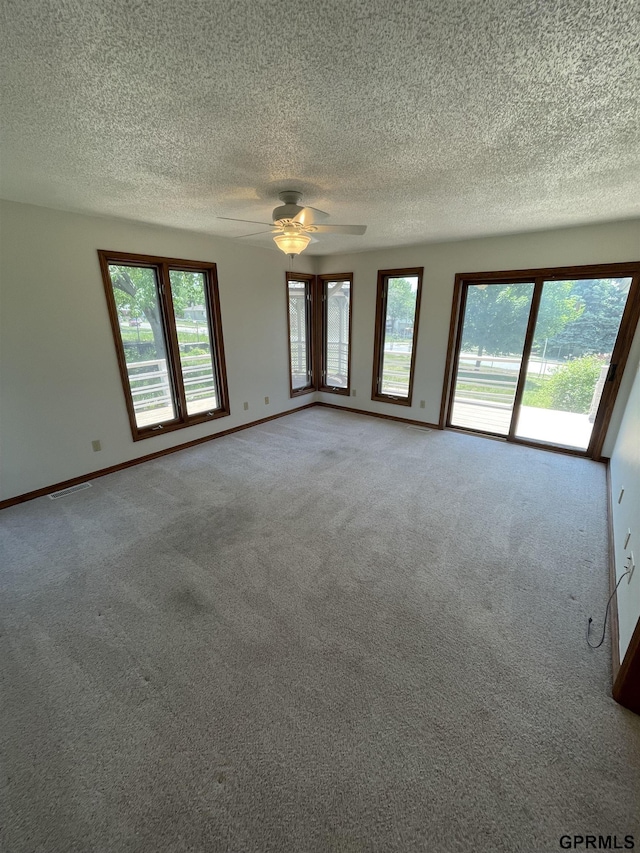 unfurnished room with ceiling fan, a textured ceiling, carpet flooring, and baseboards
