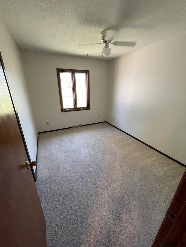 unfurnished room featuring light carpet, a textured ceiling, ceiling fan, and baseboards