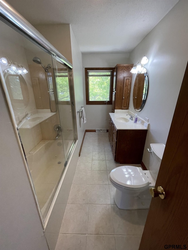 bathroom featuring tile patterned floors, toilet, a textured ceiling, enclosed tub / shower combo, and vanity