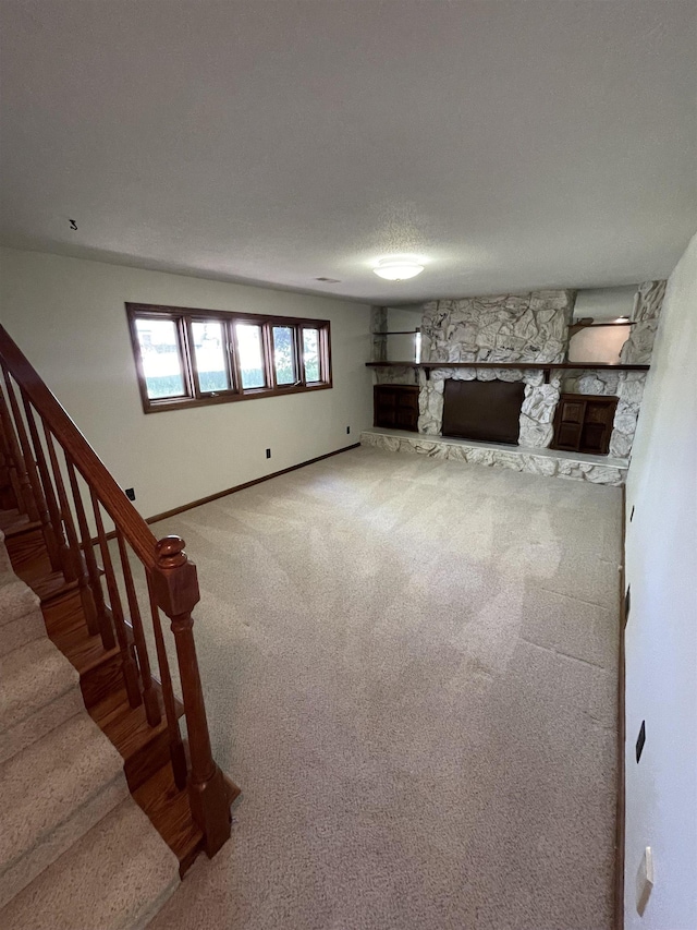unfurnished living room featuring carpet, stairway, baseboards, and a fireplace
