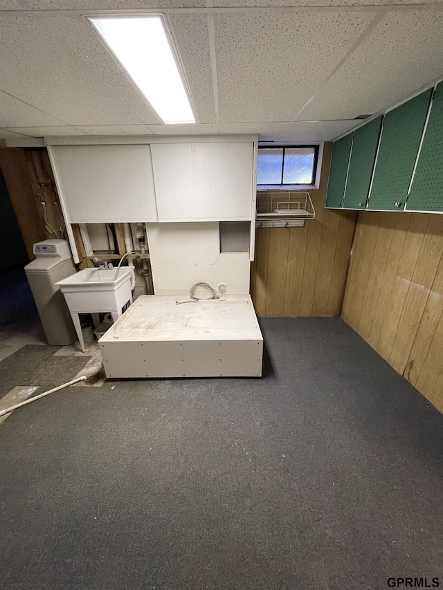 below grade area with wood walls, carpet floors, and a drop ceiling