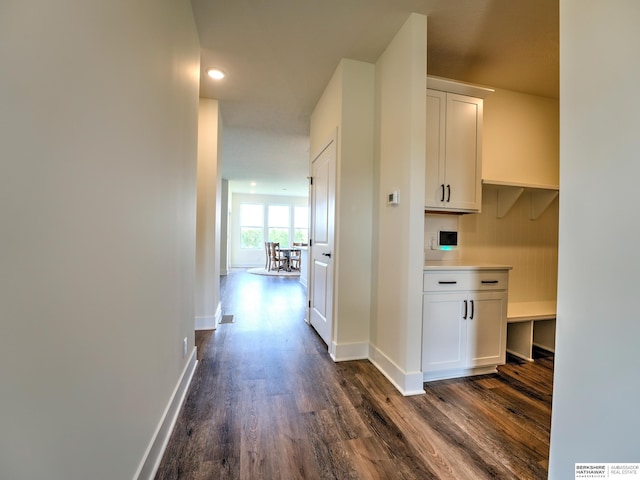 corridor with dark wood-type flooring, baseboards, and recessed lighting