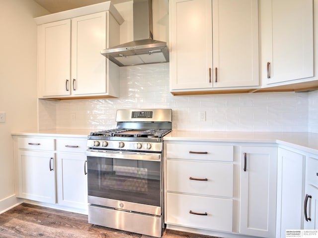 kitchen featuring stainless steel gas range oven, wall chimney range hood, light countertops, wood finished floors, and white cabinetry