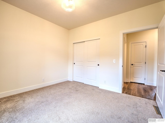 unfurnished bedroom with dark carpet, baseboards, and a closet