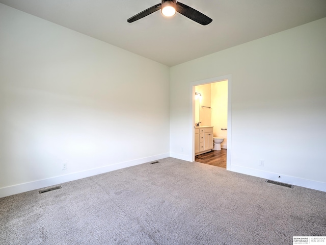 carpeted empty room featuring a ceiling fan, baseboards, and a sink