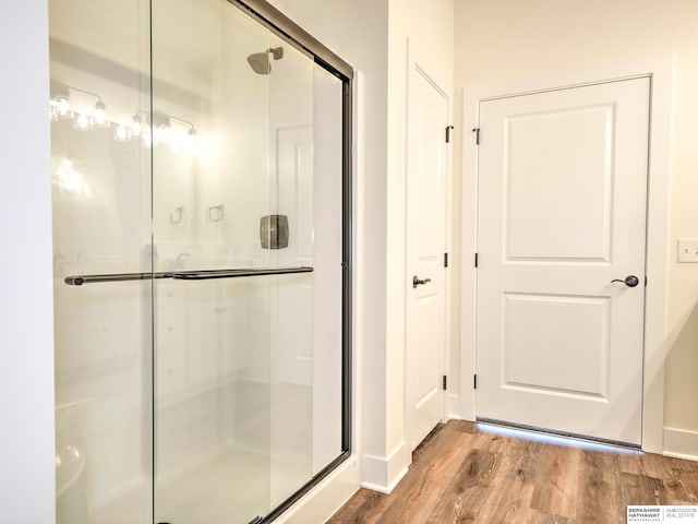 full bathroom featuring wood finished floors, a shower stall, and baseboards