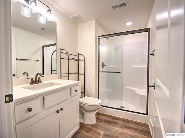 bathroom with wood finished floors, toilet, a shower stall, vanity, and recessed lighting