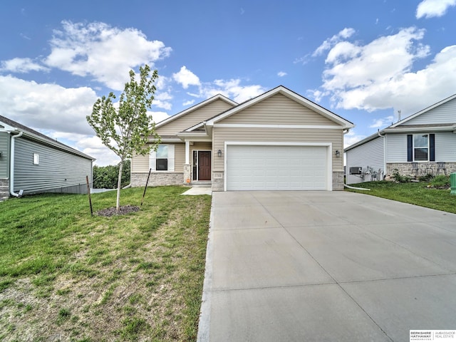view of front facade with an attached garage, concrete driveway, a front yard, and stone siding
